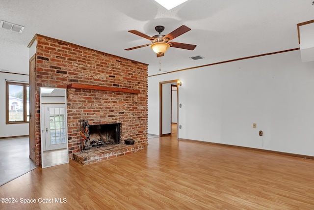 unfurnished living room featuring ceiling fan, a fireplace, ornamental molding, and light wood-type flooring