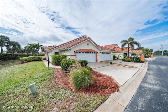 mediterranean / spanish home featuring a front yard and a garage