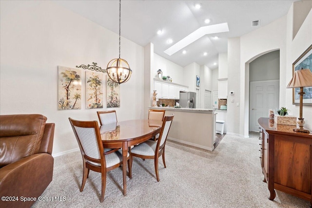 dining room with light carpet, high vaulted ceiling, and a notable chandelier