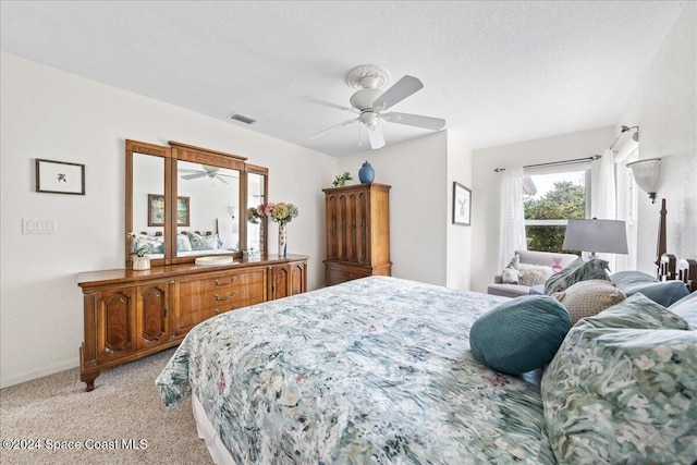 carpeted bedroom featuring ceiling fan and a textured ceiling