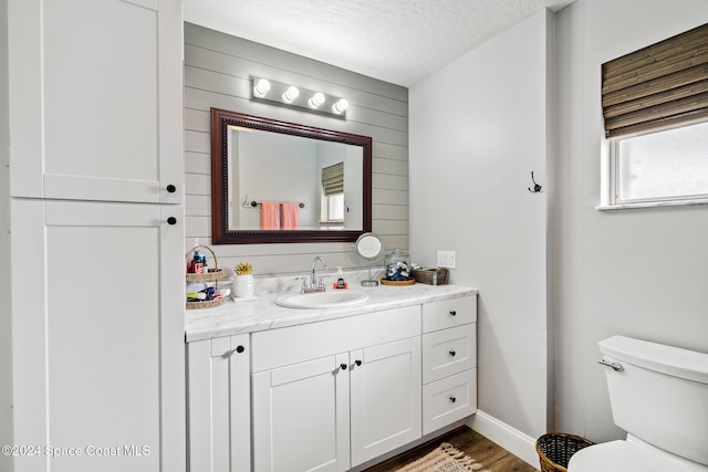 bathroom featuring vanity, toilet, wood-type flooring, and a textured ceiling