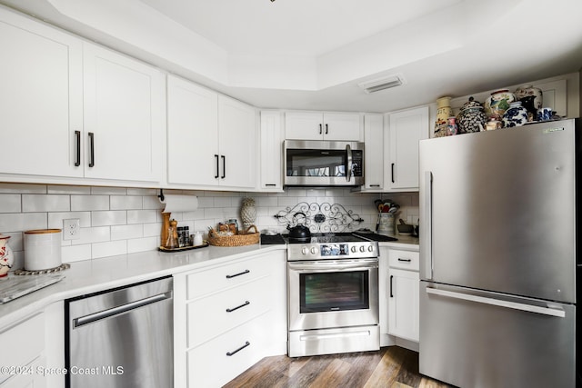 kitchen with decorative backsplash, white cabinetry, stainless steel appliances, and dark hardwood / wood-style floors