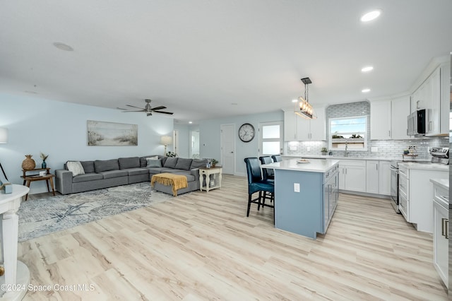 kitchen featuring white cabinetry, a center island, stainless steel appliances, a kitchen breakfast bar, and decorative light fixtures