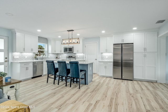 kitchen featuring pendant lighting, light hardwood / wood-style floors, white cabinets, and stainless steel appliances