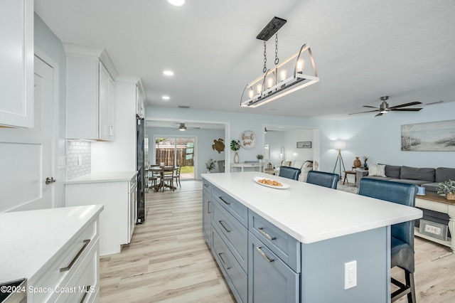 kitchen featuring a kitchen breakfast bar, white cabinets, decorative light fixtures, and a kitchen island