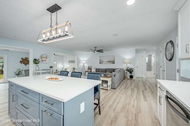 kitchen with ceiling fan, a center island, stainless steel dishwasher, pendant lighting, and a breakfast bar area