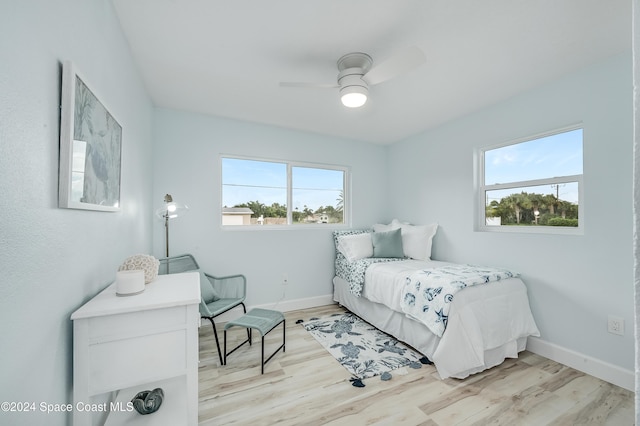 bedroom featuring ceiling fan, light hardwood / wood-style floors, and multiple windows