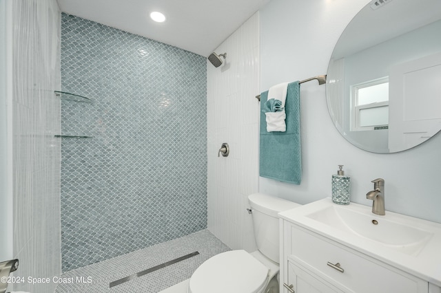 bathroom featuring vanity, toilet, and tiled shower