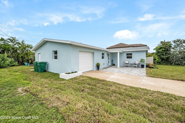 rear view of property with a patio, a yard, and a garage