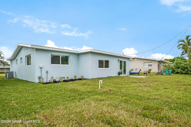 rear view of property featuring a yard and central AC unit