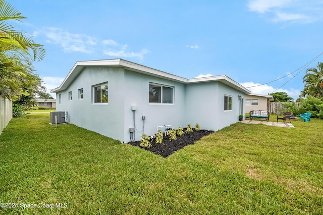 view of side of home with outdoor lounge area, cooling unit, a yard, and a patio