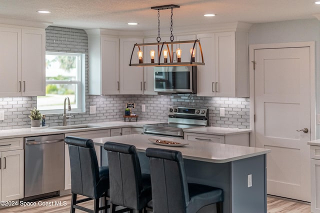 kitchen featuring a kitchen bar, stainless steel appliances, sink, a center island, and white cabinetry