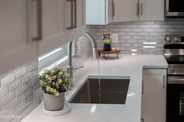 kitchen with tasteful backsplash, white cabinetry, and sink