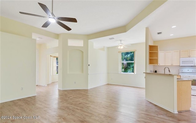 unfurnished living room with ceiling fan, sink, and light hardwood / wood-style flooring