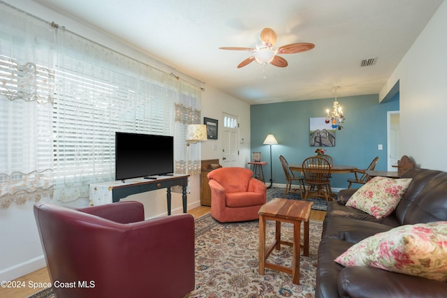 living room with light wood-type flooring and ceiling fan with notable chandelier