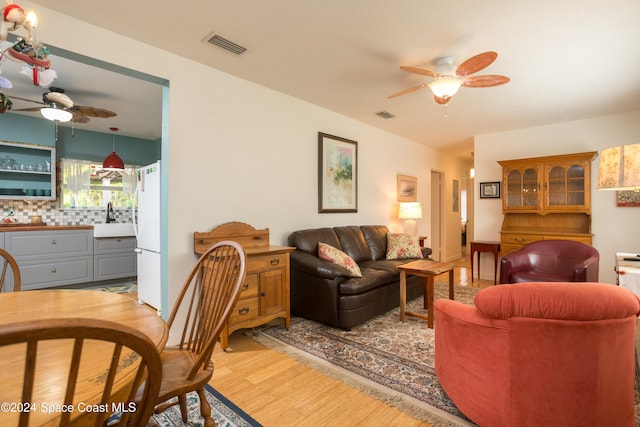 living room featuring ceiling fan, light hardwood / wood-style floors, and sink