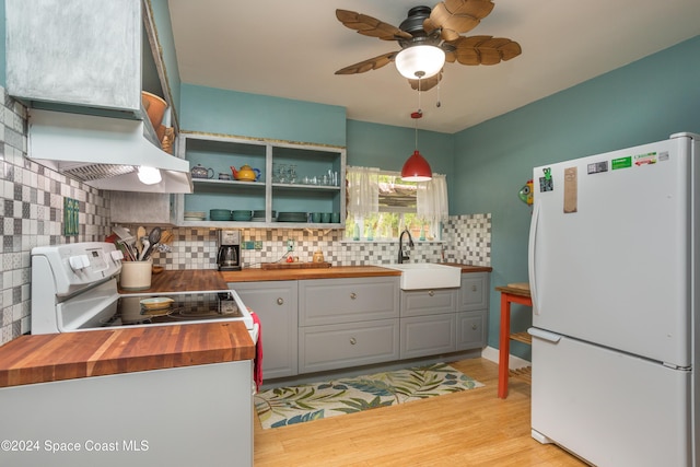 kitchen featuring wood counters, white appliances, sink, hanging light fixtures, and light wood-type flooring