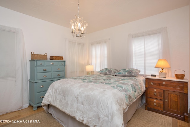 bedroom featuring an inviting chandelier and light hardwood / wood-style flooring