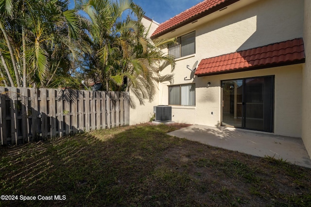 rear view of property with a yard, a patio, and central AC