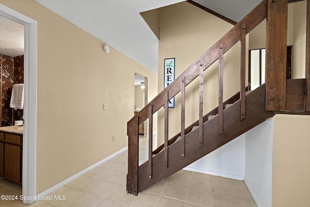 stairway featuring a textured ceiling and tile patterned floors