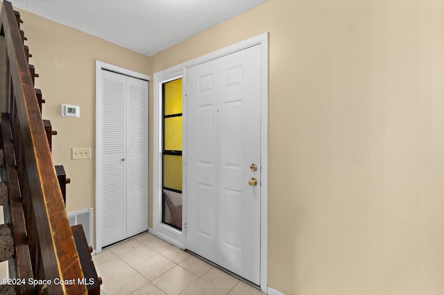 foyer entrance featuring light tile patterned floors and a textured ceiling