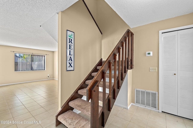 stairs with tile patterned flooring and a textured ceiling