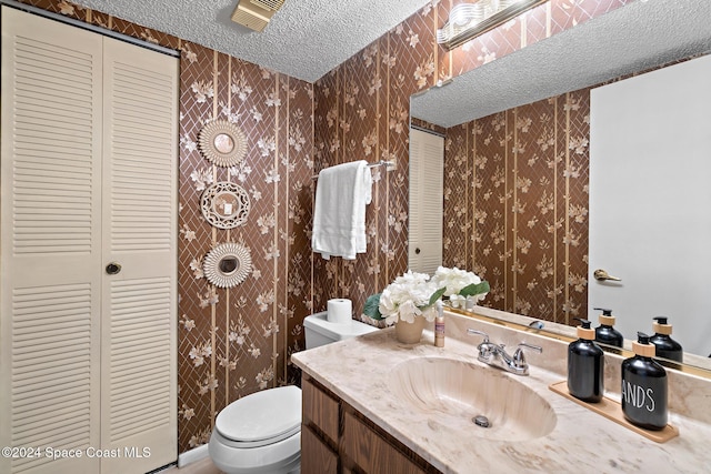 bathroom with vanity, toilet, and a textured ceiling