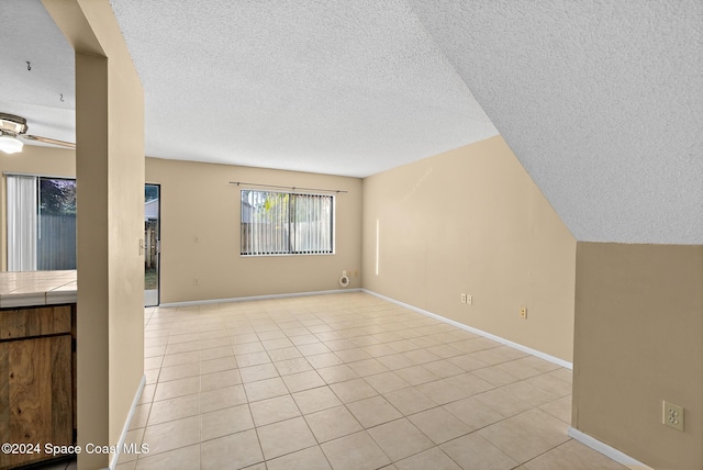 unfurnished living room featuring light tile patterned floors, a textured ceiling, and ceiling fan