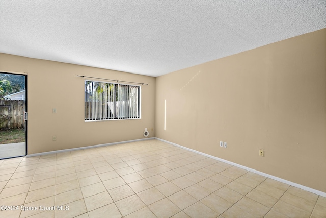 empty room with light tile patterned flooring and a textured ceiling