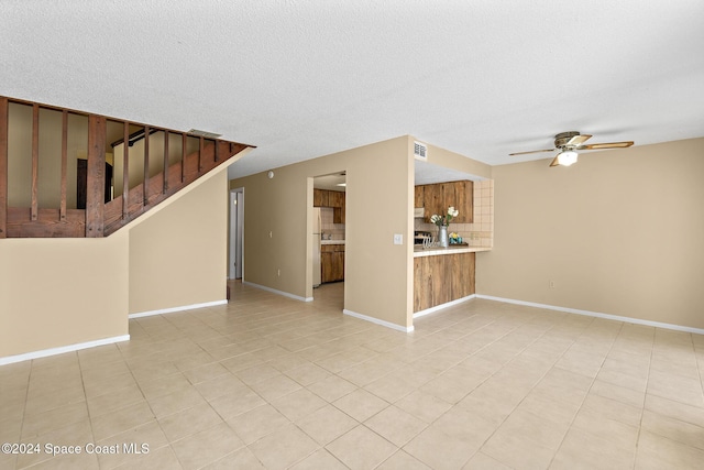 unfurnished living room featuring ceiling fan, light tile patterned floors, and a textured ceiling