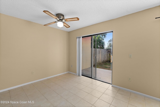 tiled empty room featuring ceiling fan and a textured ceiling