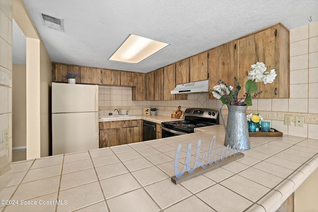 kitchen featuring electric range, tile counters, white refrigerator, and decorative backsplash