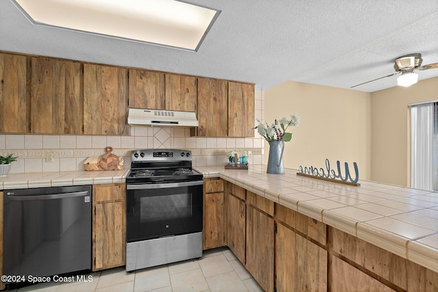 kitchen featuring appliances with stainless steel finishes, tasteful backsplash, tile counters, and ceiling fan