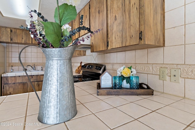 details with backsplash, tile counters, and electric stove