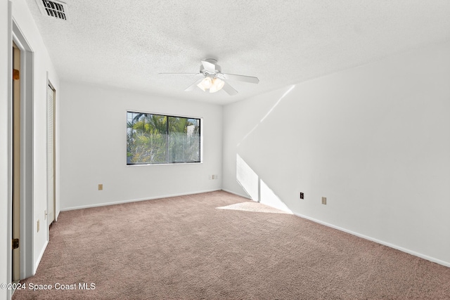 unfurnished bedroom with a textured ceiling, ceiling fan, light carpet, and a closet