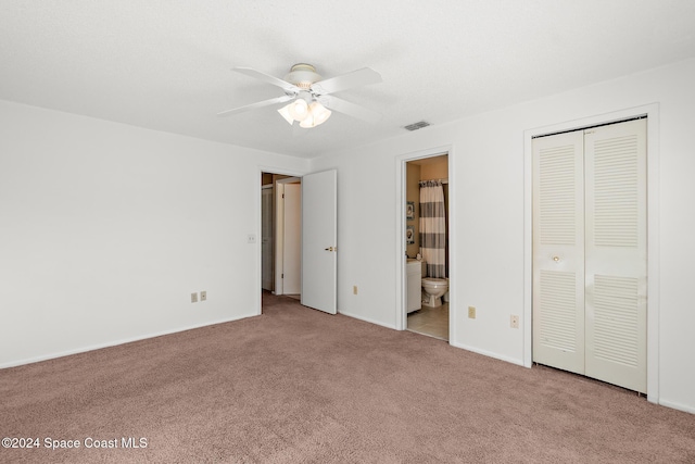 unfurnished bedroom with a closet, ensuite bathroom, ceiling fan, and light colored carpet