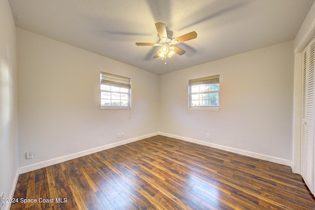 unfurnished bedroom with ceiling fan, dark hardwood / wood-style floors, and multiple windows