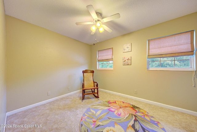 sitting room with a wealth of natural light, ceiling fan, and light colored carpet