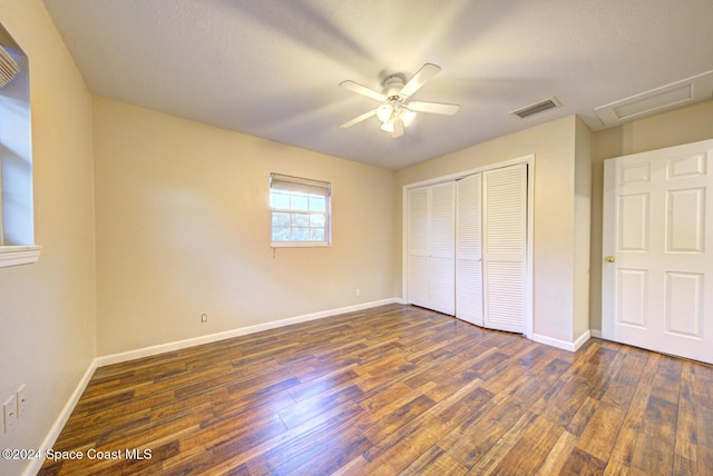 unfurnished bedroom featuring a textured ceiling, a closet, dark hardwood / wood-style floors, and ceiling fan