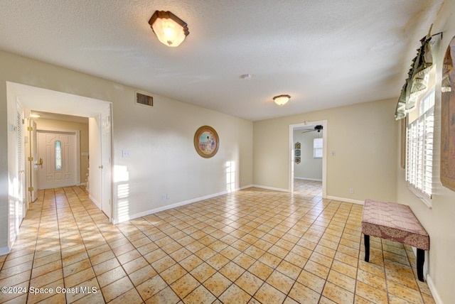 tiled spare room featuring a textured ceiling