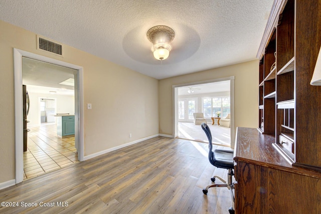 unfurnished office with ceiling fan, wood-type flooring, and a textured ceiling