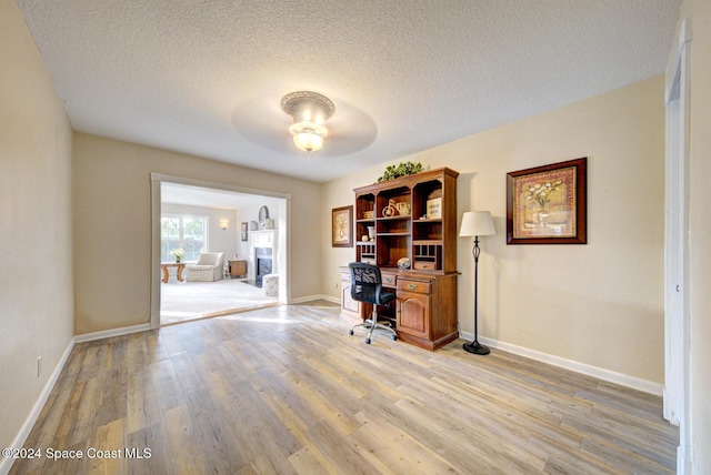 unfurnished office featuring ceiling fan, a textured ceiling, and light hardwood / wood-style flooring