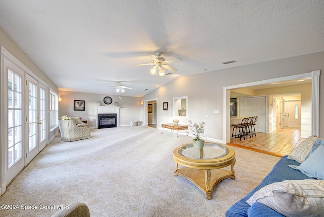 living room featuring light carpet, french doors, a textured ceiling, vaulted ceiling, and ceiling fan