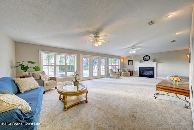 carpeted living room featuring ceiling fan, a textured ceiling, a wealth of natural light, and french doors