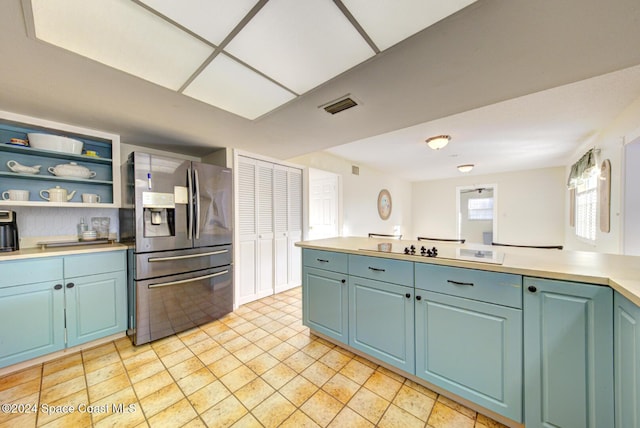 kitchen featuring blue cabinetry, stainless steel fridge, and white cooktop