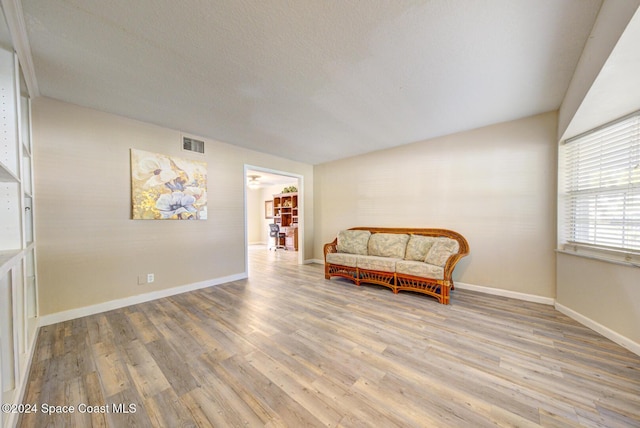 living area with a textured ceiling and light hardwood / wood-style flooring