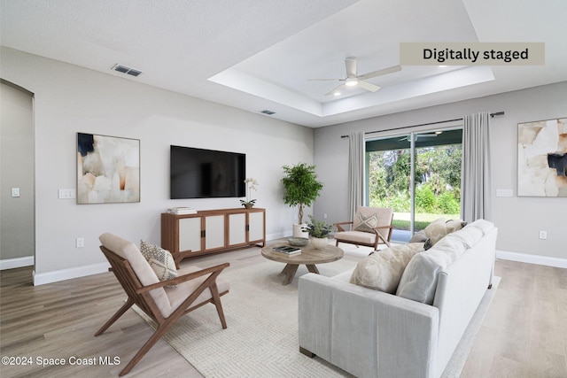 living room featuring a tray ceiling, ceiling fan, and hardwood / wood-style flooring