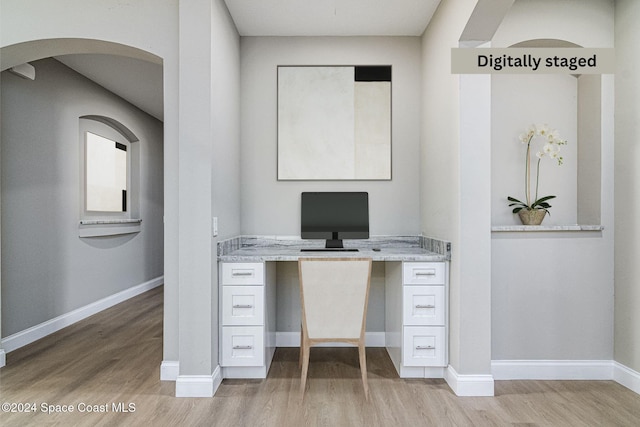 unfurnished office featuring built in desk and wood-type flooring