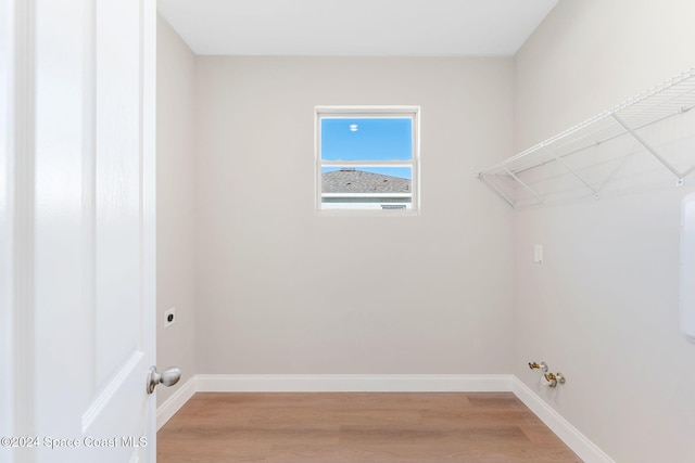 clothes washing area featuring hookup for an electric dryer, gas dryer hookup, and light hardwood / wood-style flooring