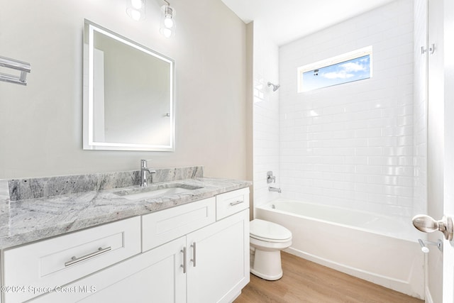 full bathroom featuring vanity, hardwood / wood-style flooring, toilet, and tiled shower / bath combo